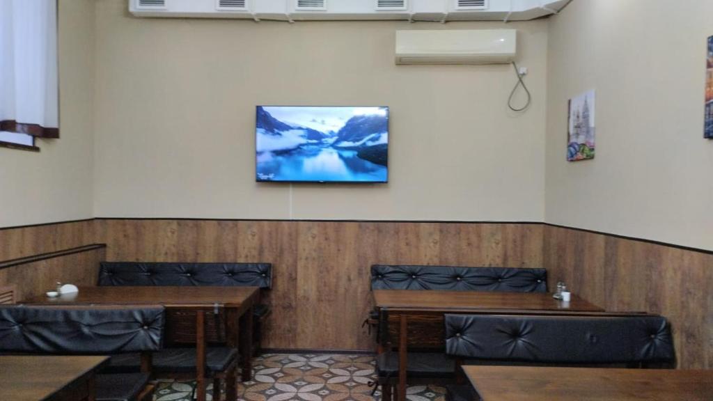 乌斯季卡缅诺戈尔斯克Ак-Тай Гостиный Двор的一间设有两张桌子的房间和墙上的电视