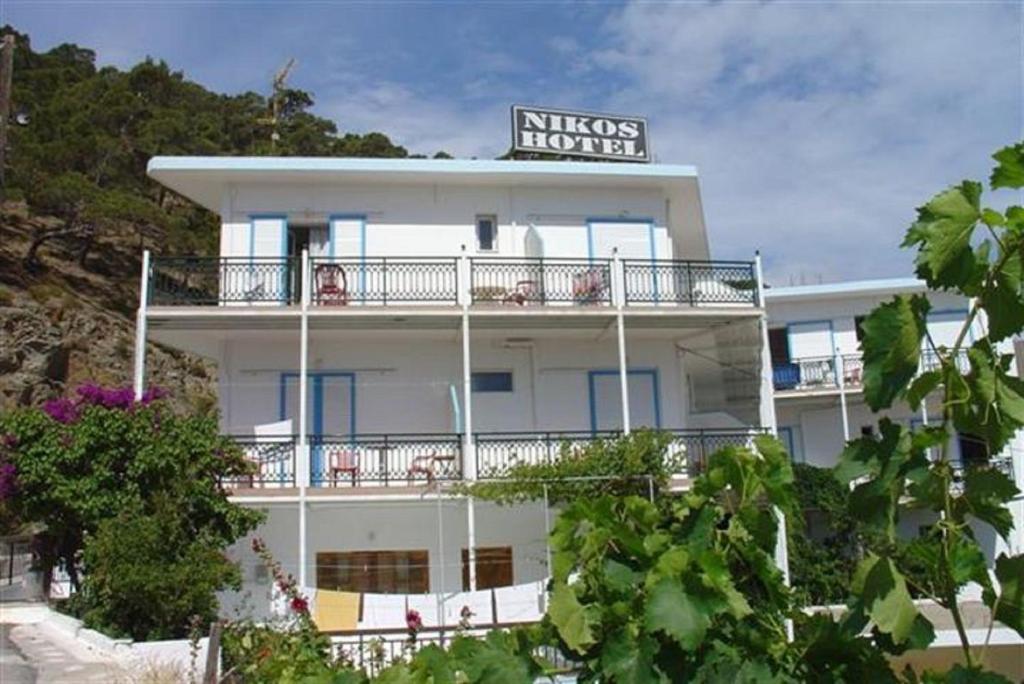 迪亚法尼Nikos Hotel的白色的建筑,上面有标志