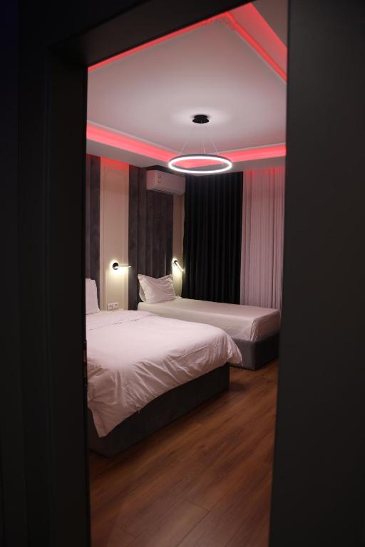KukësSky View Hotel & Restaurant的红色灯光客房内的两张床