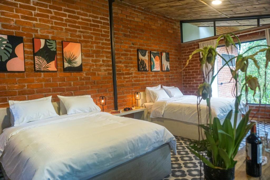 ArchidonaPacha Eco Lodge Glamping & Hotel的一间卧室设有两张床和砖墙