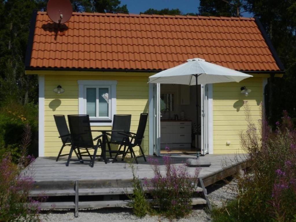 LjugarnKleines Ferienhaus - Tiny house - auf Gotland 700 Meter zum Meer的一座黄色的小房子,配有椅子和雨伞