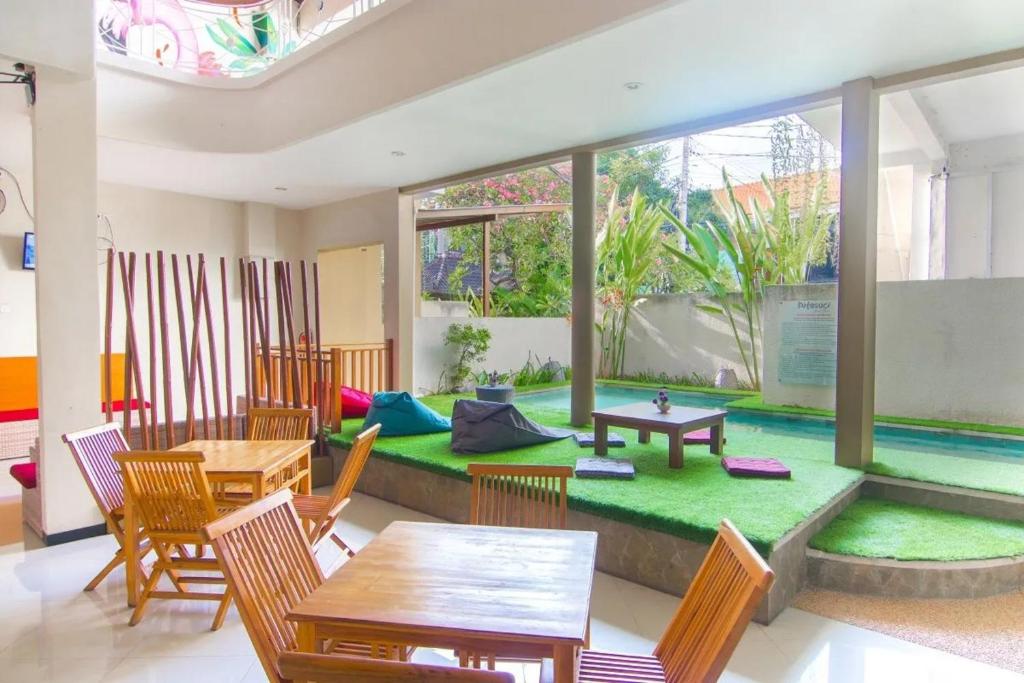 库塔Kuta Suci Guesthouse的一间带桌椅的客厅和一个游泳池