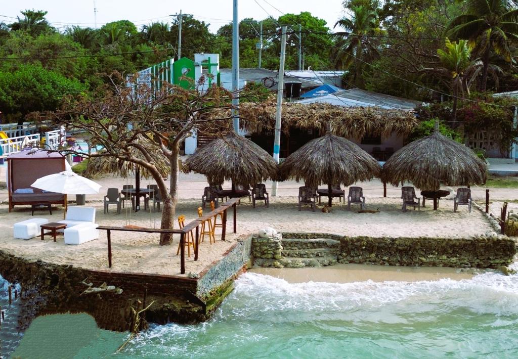Playa Punta ArenaPunta Arena Beach Hostel的海滩上设有桌子和草伞及椅子