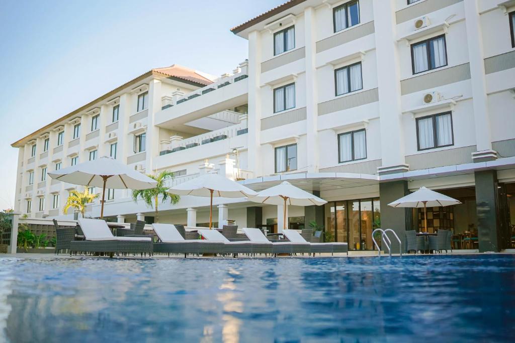 古邦Sahid T-More Hotel的酒店设有带椅子和遮阳伞的游泳池
