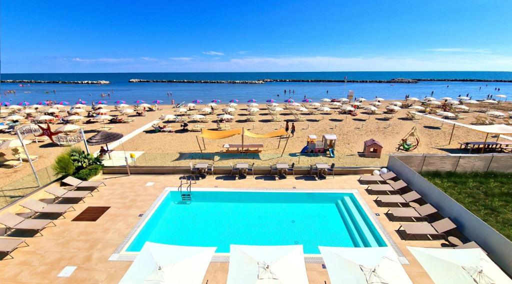 里米尼You & Me Beach Hotel的享有海滩美景,设有游泳池和遮阳伞