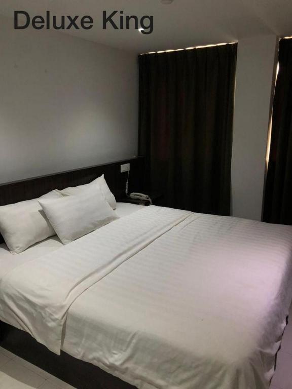 太平Hotel Vistana Micassa的卧室内的一张带白色床单和枕头的床