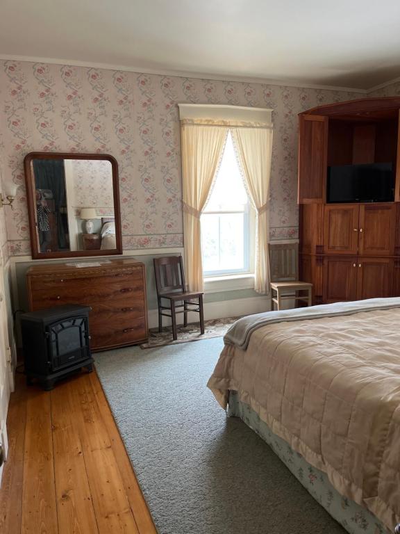 拉特兰Antique Mansion B & B的一间卧室配有一张床、梳妆台和镜子