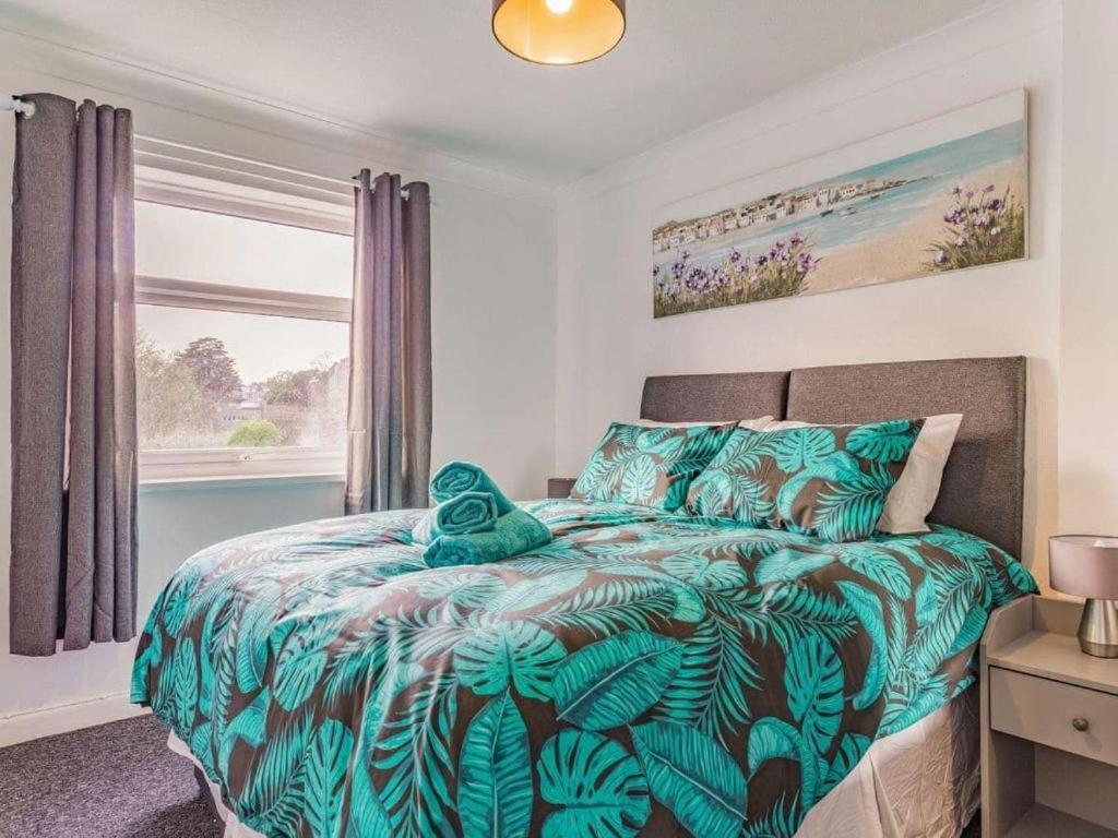 托基Lovely Magnolia Accommodation 3king Torquay的一间卧室配有一张带绿色棉被的床和窗户。