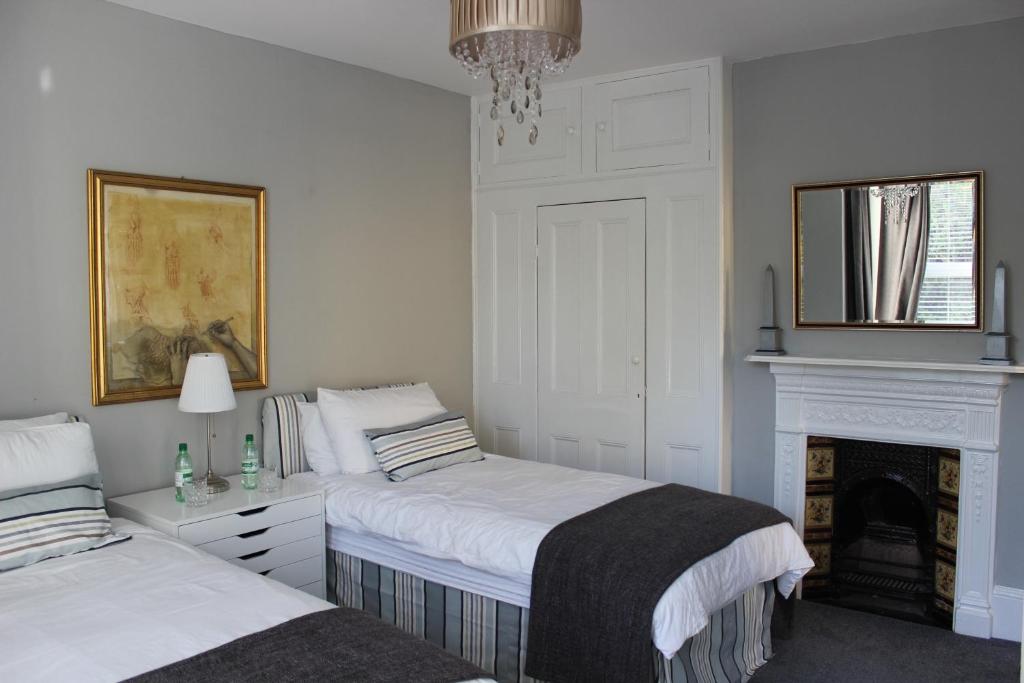 罗切斯特Botleigh Villa的一间白色卧室,配有两张床和壁炉