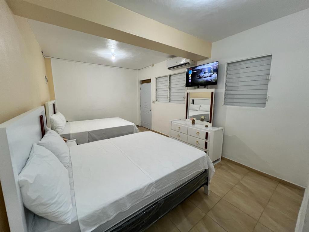 Azua de CompostelaHabitación doble Villa Marchena Azua的一间卧室配有两张床和一台平面电视
