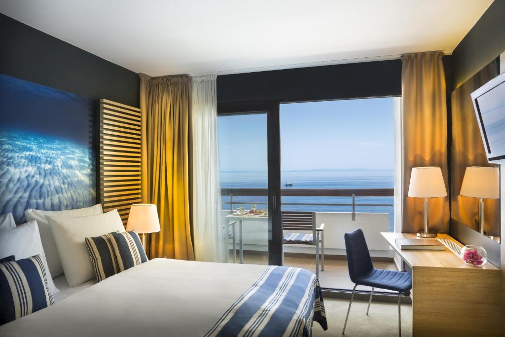 奥帕提亚Hotel Admiral - Liburnia的酒店客房设有一张床、一张书桌和一个阳台。