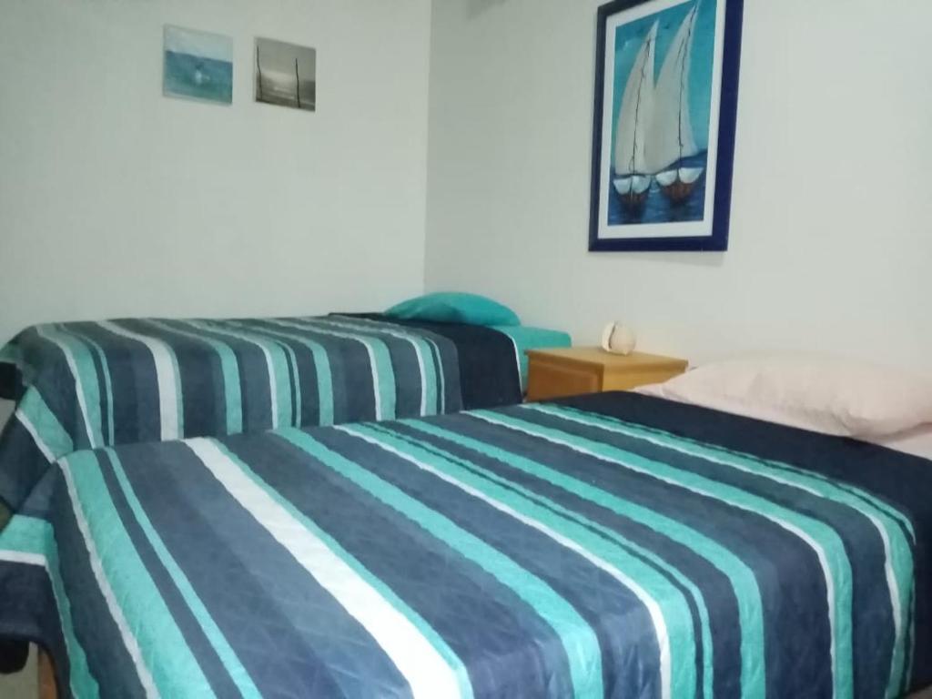 La BocanaHospedaje La Estancia Punta Sal的配有条纹床罩的酒店客房内的两张床