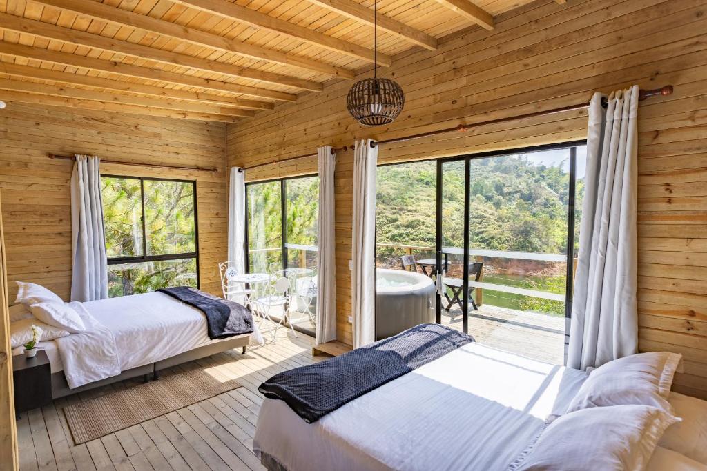 瓜塔佩Cabañas Refugio Himalaya的一间带两张床的卧室和一个带浴缸的阳台