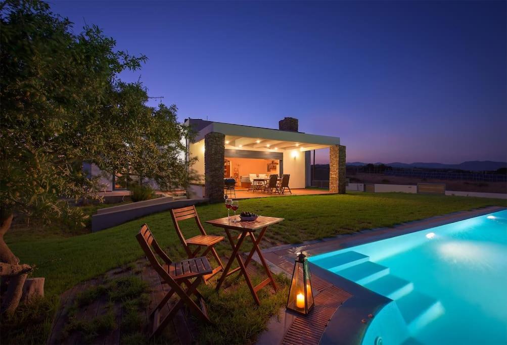 拉卡尼亚Cristelia seafront & pool villa的游泳池旁带桌椅的后院