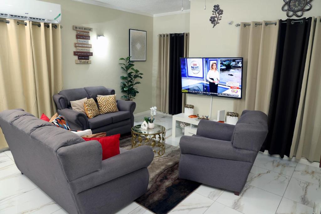 金斯敦Spacious Luxury 3 Bed Rooms in Kingston的客厅配有2把椅子和平面电视