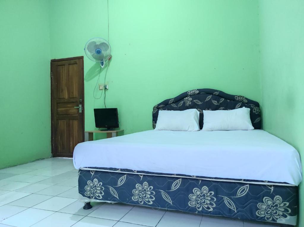KaremaOYO 93411 Syariah Hotel Tomborang的一间卧室配有一张床和风扇