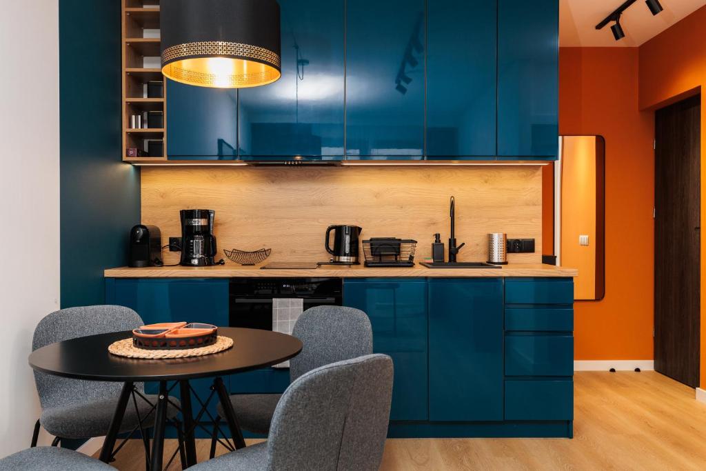 克拉科夫Colorful Cracovia Apartments By Upstairs的厨房配有蓝色橱柜和桌椅