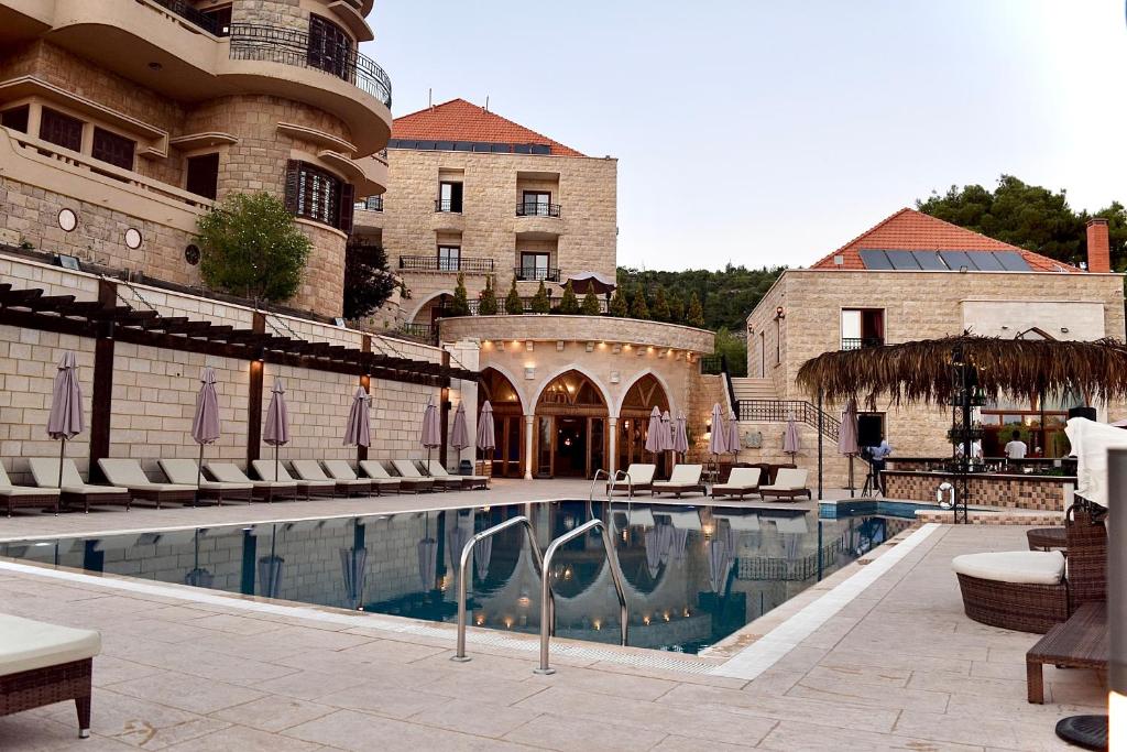 代埃尔卡马尔L'auberge des Emirs的酒店游泳池设有椅子,酒店大楼