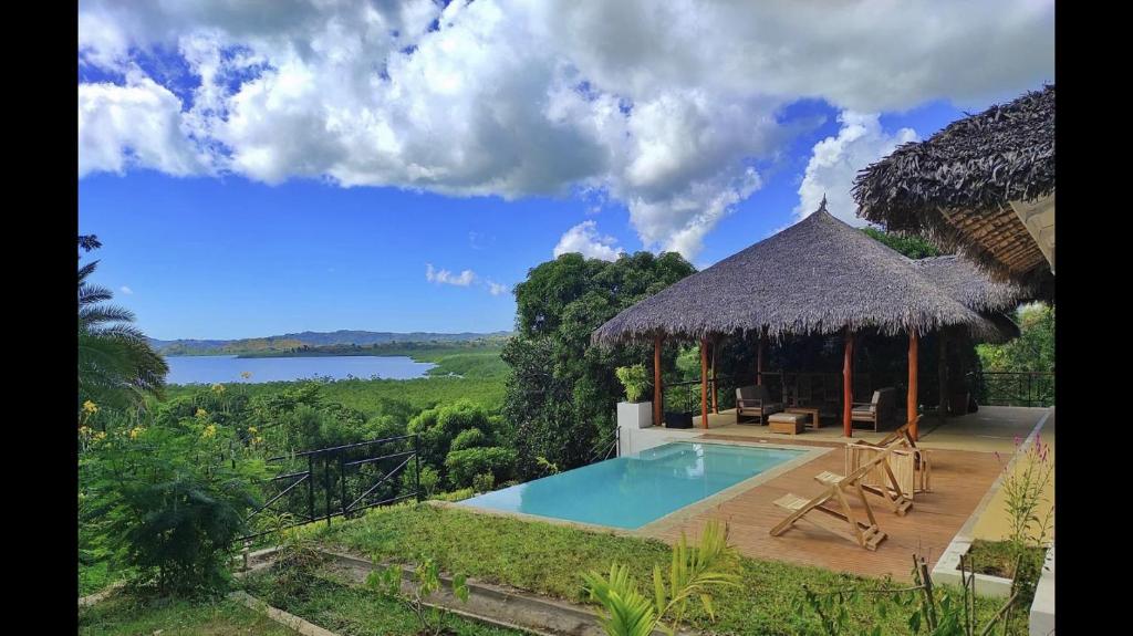 贝岛Villa Agay的一座带游泳池和茅草屋顶的别墅