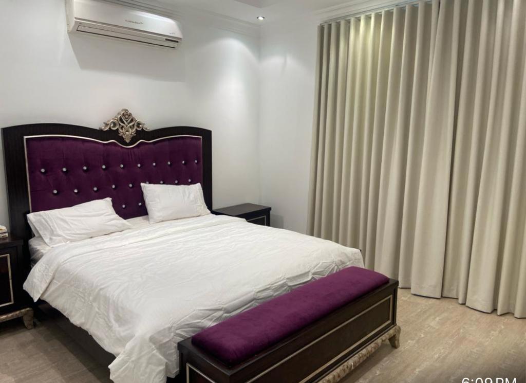 利雅德Alwaha-Appartement的一间卧室配有一张大床和紫色床头板