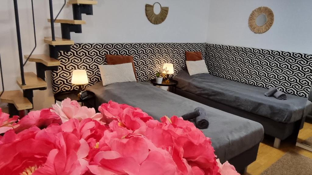 布达佩斯Bercsényi apartments - close to the Gellért Thermal Bath的客厅配有两张床和粉红色的鲜花