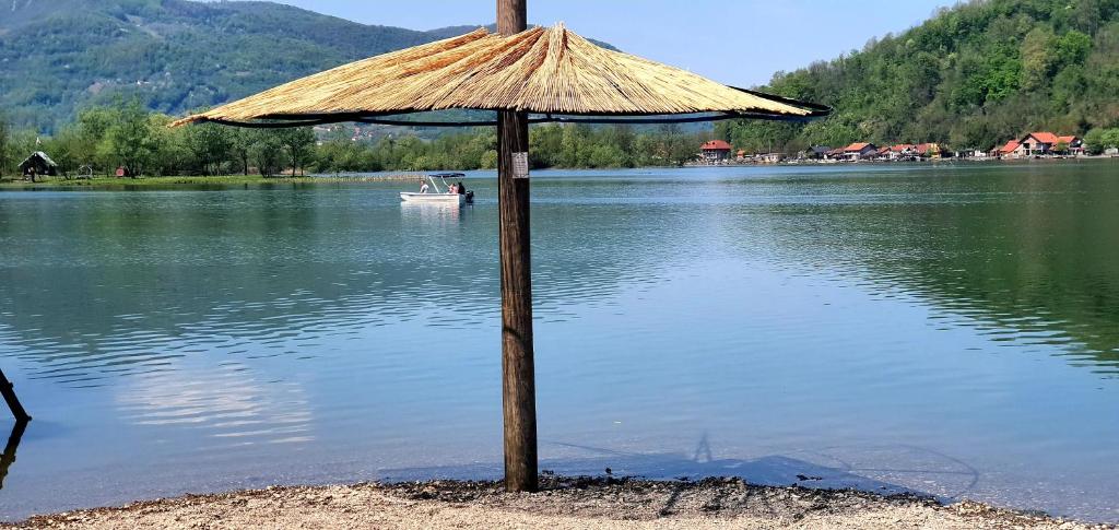兹沃尔尼克Kuca za odmor Stakic的坐在湖中的一个草伞