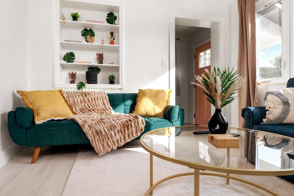 盖恩斯维尔Smart Bungalow: 10-min to UF, Central Location的客厅配有绿色沙发和玻璃桌