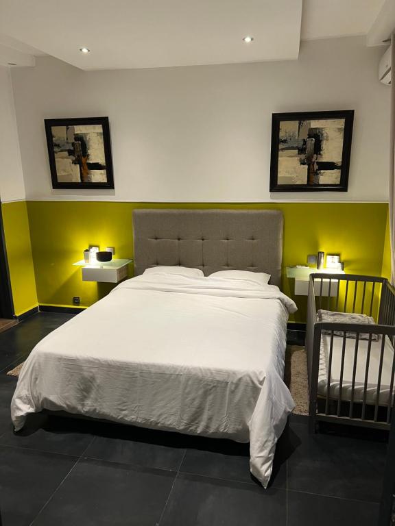 达喀尔Meublé Nord Foire Dakar的卧室设有一张白色大床和黄色的墙壁