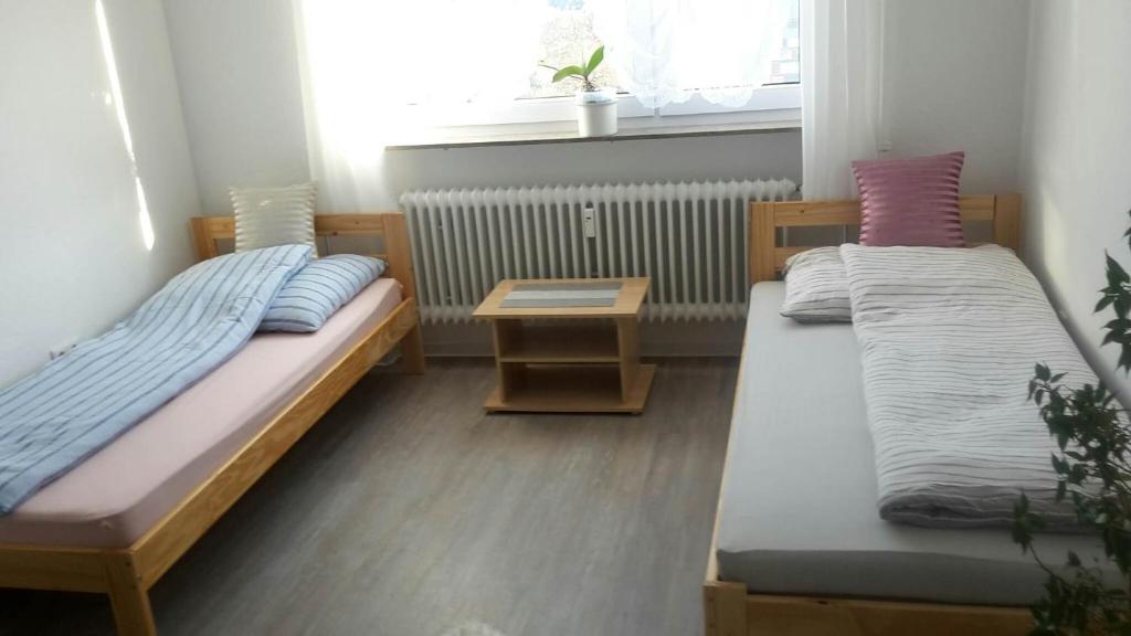 斯图加特Otthonos Szállás的客房设有两张床、一张桌子和一扇窗户。