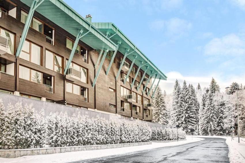 布拉索夫Penthouse Silver Mountain, Duplex 3 camere - 250 mp luxury garden - Poiana Brasov的前面有雪覆盖的树木的建筑