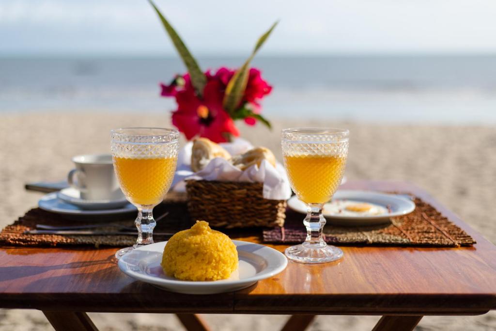 普雷亚Casa PESQUEIRA Preá - Frente Mar!的一张桌子,上面放着两杯橙汁和一些食物