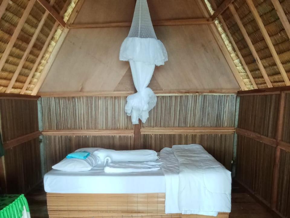 FamOr Mandira Guest House的一张位于带蚊帐的木制客房内的床铺