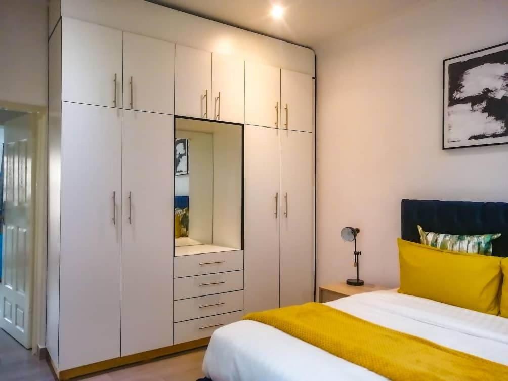 利隆圭Crystal Apartments Area 43的卧室配有白色橱柜和黄色的床。