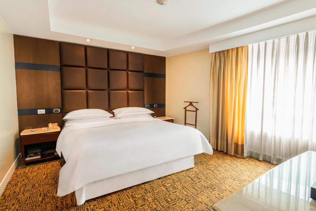 瓜亚基尔喜来登瓜亚基尔酒店的卧室设有白色的床和大窗户