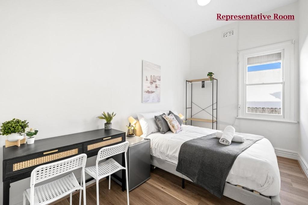 悉尼Premier Leichhardt Stayz的卧室配有一张床、一张桌子和椅子