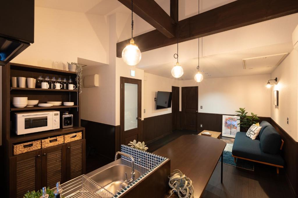 丰冈市城崎温泉一棟貸し　旅宿YaDOKARI的厨房以及带桌子和沙发的客厅。