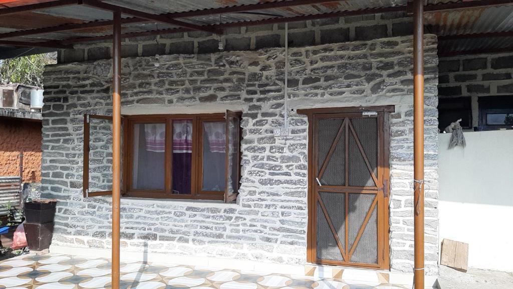 博卡拉HIMALAYAN AAMA APARTMENT的石屋,带两个窗户和门