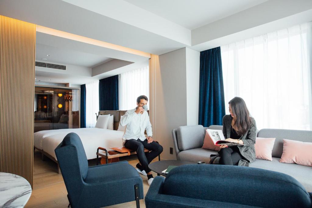 东京NOHGA HOTEL UENO TOKYO的坐在酒店房间的男女