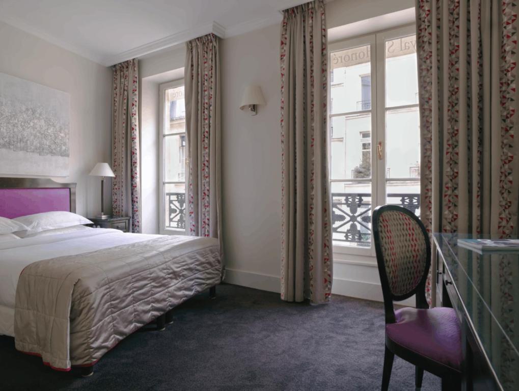巴黎Hotel Royal Saint Honore Paris Louvre的一间卧室设有床、两扇窗户和一把椅子