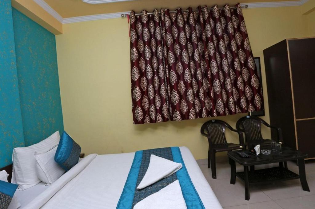 新德里Hotel Airport Plaza near Airport的一间卧室配有一张床、一张桌子和一个窗户。