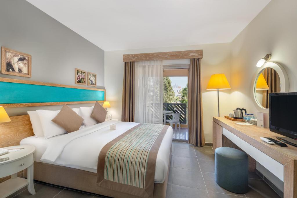 锡德Labranda Excelsior Hotel的酒店客房配有一张床、一张书桌和一台电视。