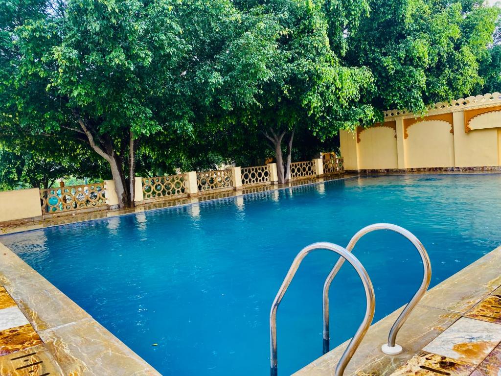 乌代浦Udai Valley Resort- Top Rated Resort in Udaipur with mountain view的一个种有树木的大型蓝色游泳池