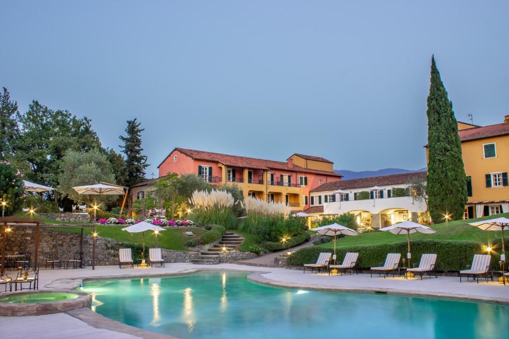 加尔伦达La Meridiana Hotel & Golf Resort的庭院内的游泳池,配有椅子和遮阳伞