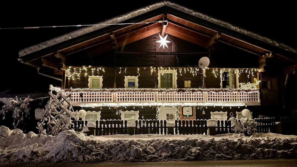 WagenhamFerienwohnung Rosenheim的雪中以圣诞灯装饰的房子