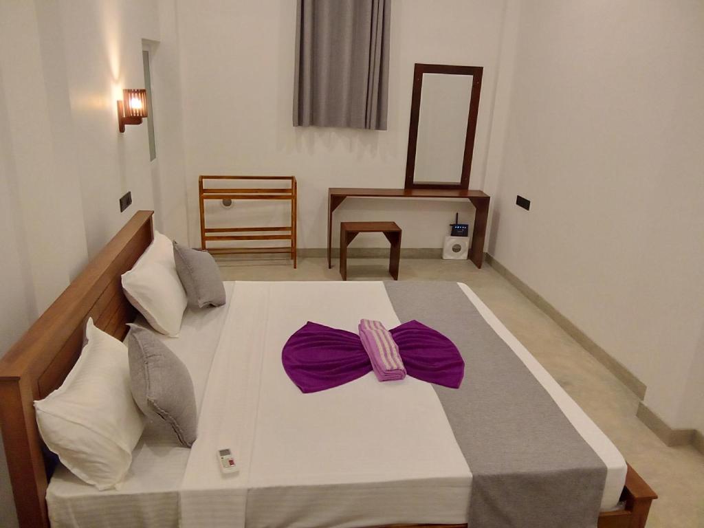 米瑞莎LaRoy Mirissa- Introducing Smart Room的一间卧室配有一张带紫色弓的大型白色床