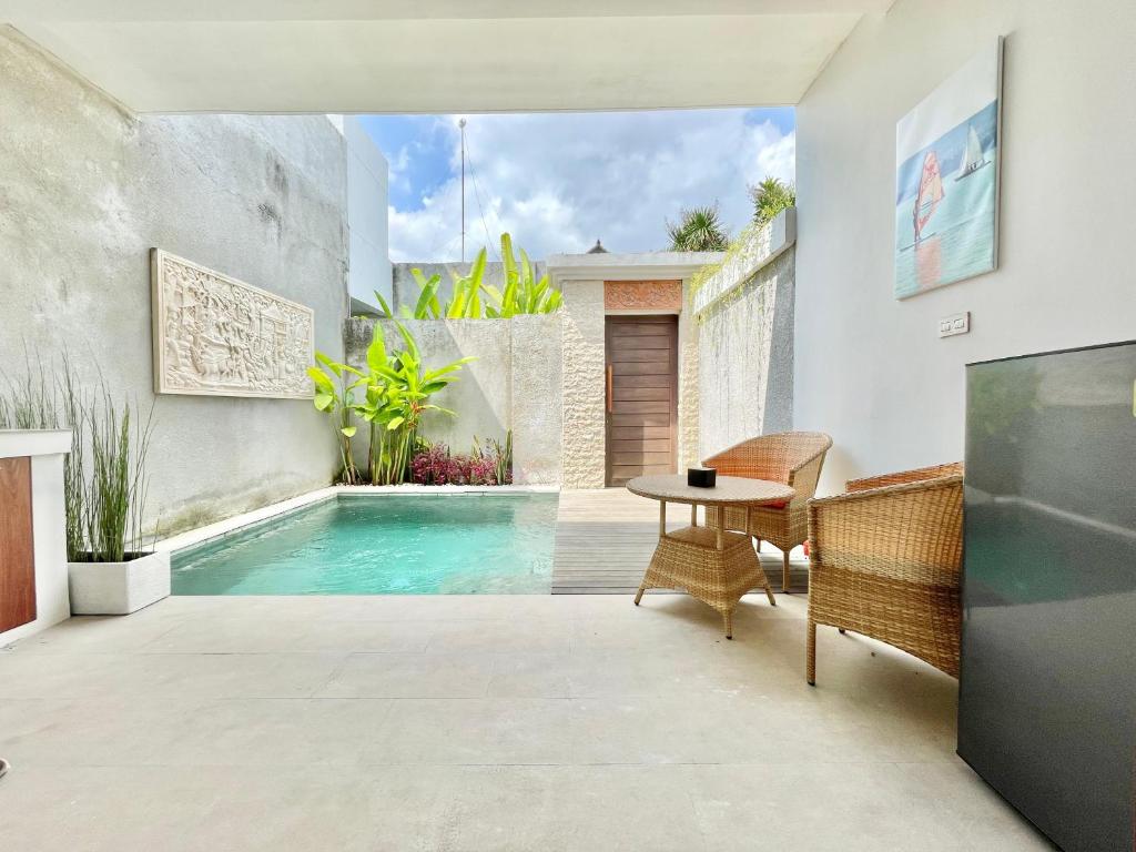 登巴萨Livin Sanur Villa的庭院设有游泳池、桌子和椅子。