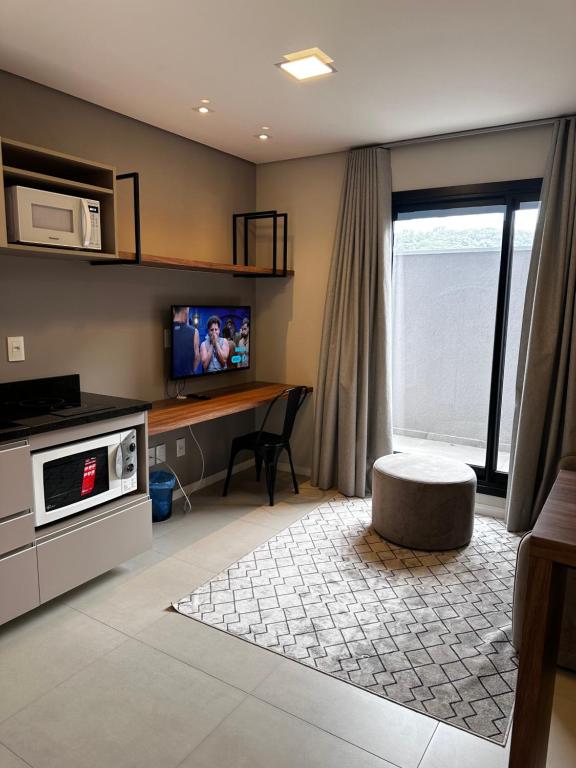 新汉堡市STUDIO Perto da feevale campus 2的客厅配有电视和带微波炉的桌子。