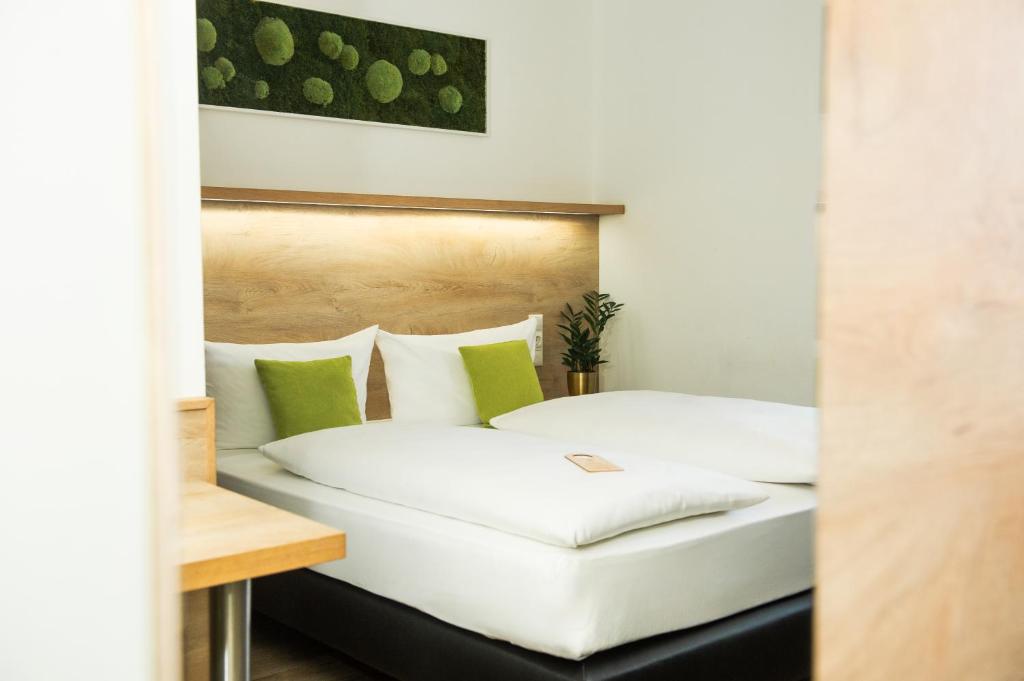 慕尼黑Hotel Perlach Allee by Blattl的一间卧室配有两张白色床和绿色枕头