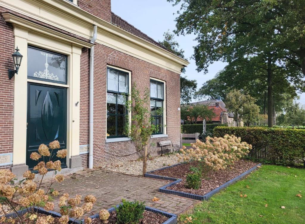 鲁茵乌尔德De Bloesemstee - Rustic Manor Farmhouse The Netherlands的前面有花园的房子