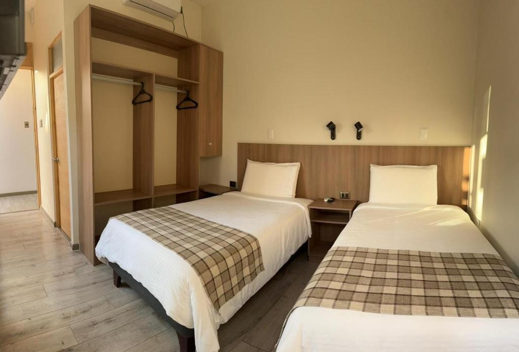 伊基克Vistara Suites的配有两张床的酒店客房中的两张床